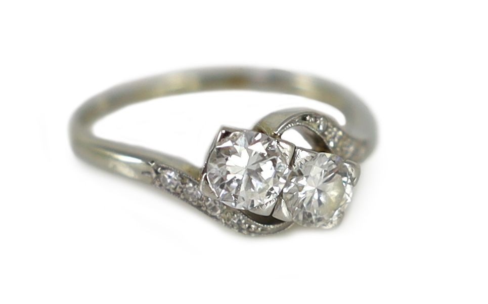 An 18ct gold and two stone diamond crossover ring, with millegrain diamond chip set shoulders